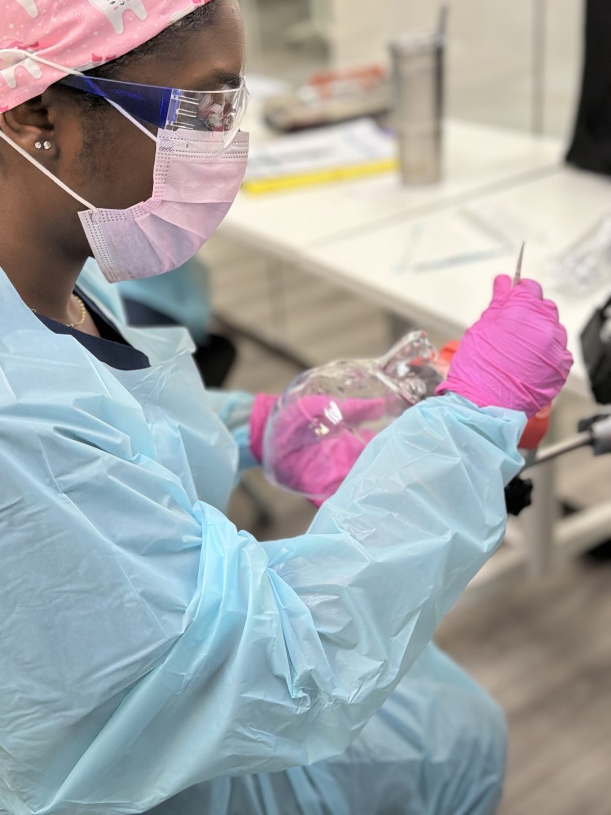 A dental assistant student in full PPE practicing on a typodont